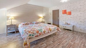 A bedroom with a bed, two bedside tables, a nightstand, a dresser, and a door.