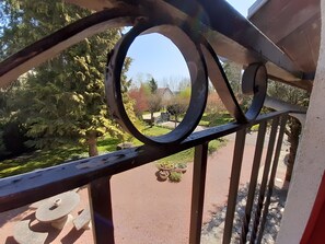 A metal railing with a circular cutout, a paved path, and potted plants in a garden setting.