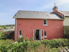 A two-story house with a red exterior, a tiled roof, and a visible chimney. - Tracey Cottage (Newton Abbot)