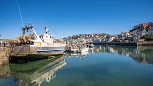 A harbor with boats, a calm water body, and a town with buildings in the background. - Tracey Cottage (Newton Abbot)