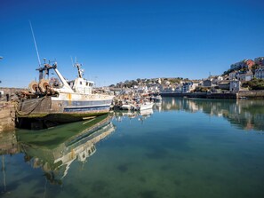 A harbor with boats, a calm water body, and a town with buildings in the background. - Tracey Cottage (Newton Abbot)