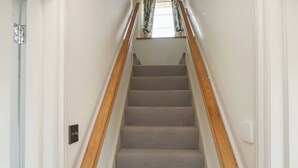 A staircase with wooden handrails and grey carpeted steps. - Tracey Cottage (Newton Abbot)