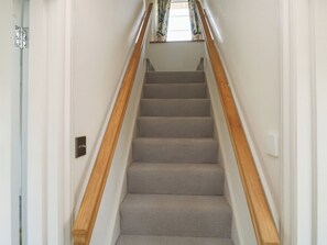 A staircase with wooden handrails and grey carpeted steps. - Tracey Cottage (Newton Abbot)