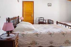 Ein Schlafzimmer mit einem hölzernen Bett, einem Nachttisch, einem Sessel und einer Tür.