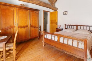 Un dormitorio con cama, armario y escritorio de madera, además de una silla.