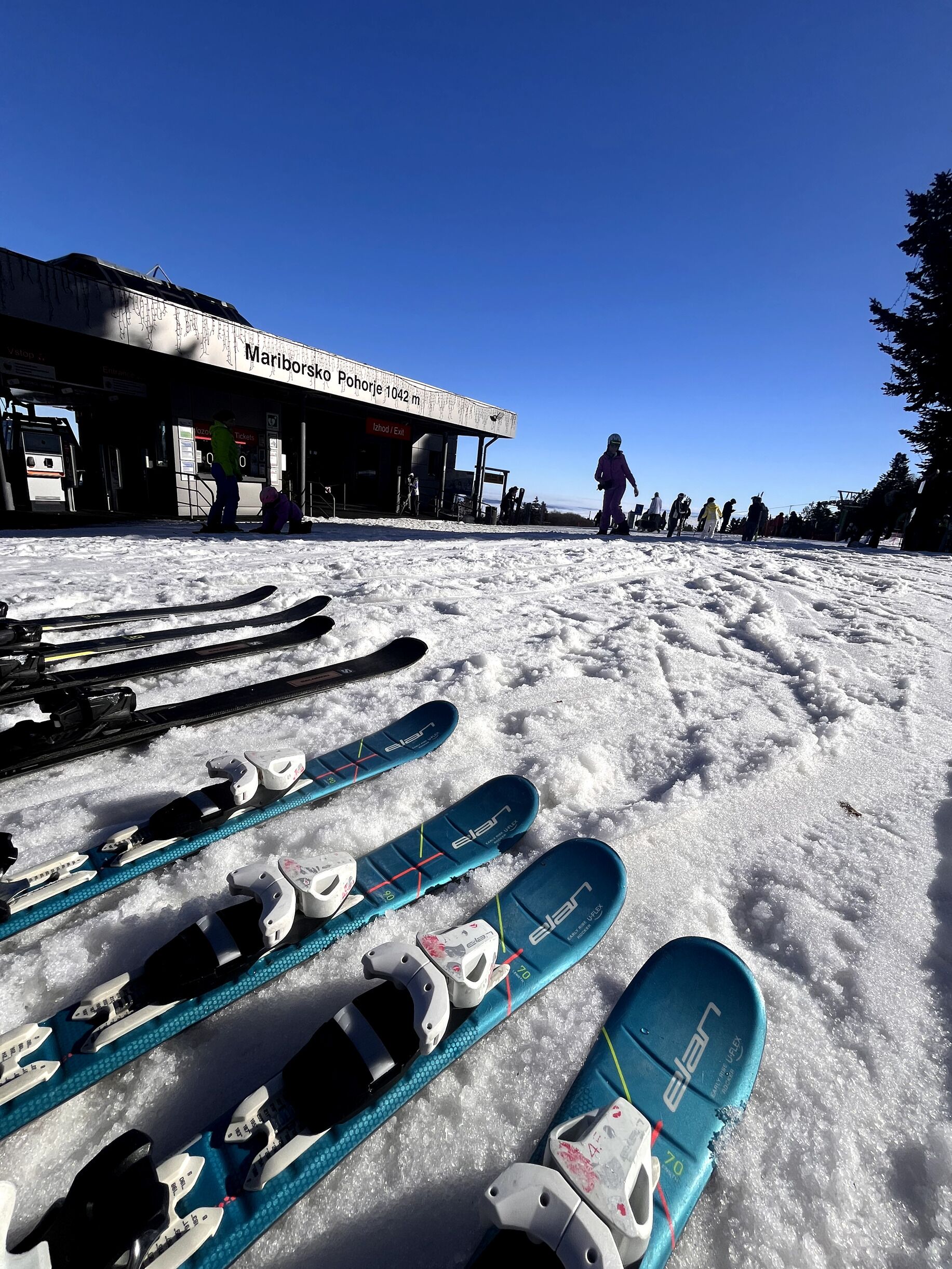 A ski resort with a building labeled 'Mariborsko Pohorje 1042 m' and a ski lift in operation.