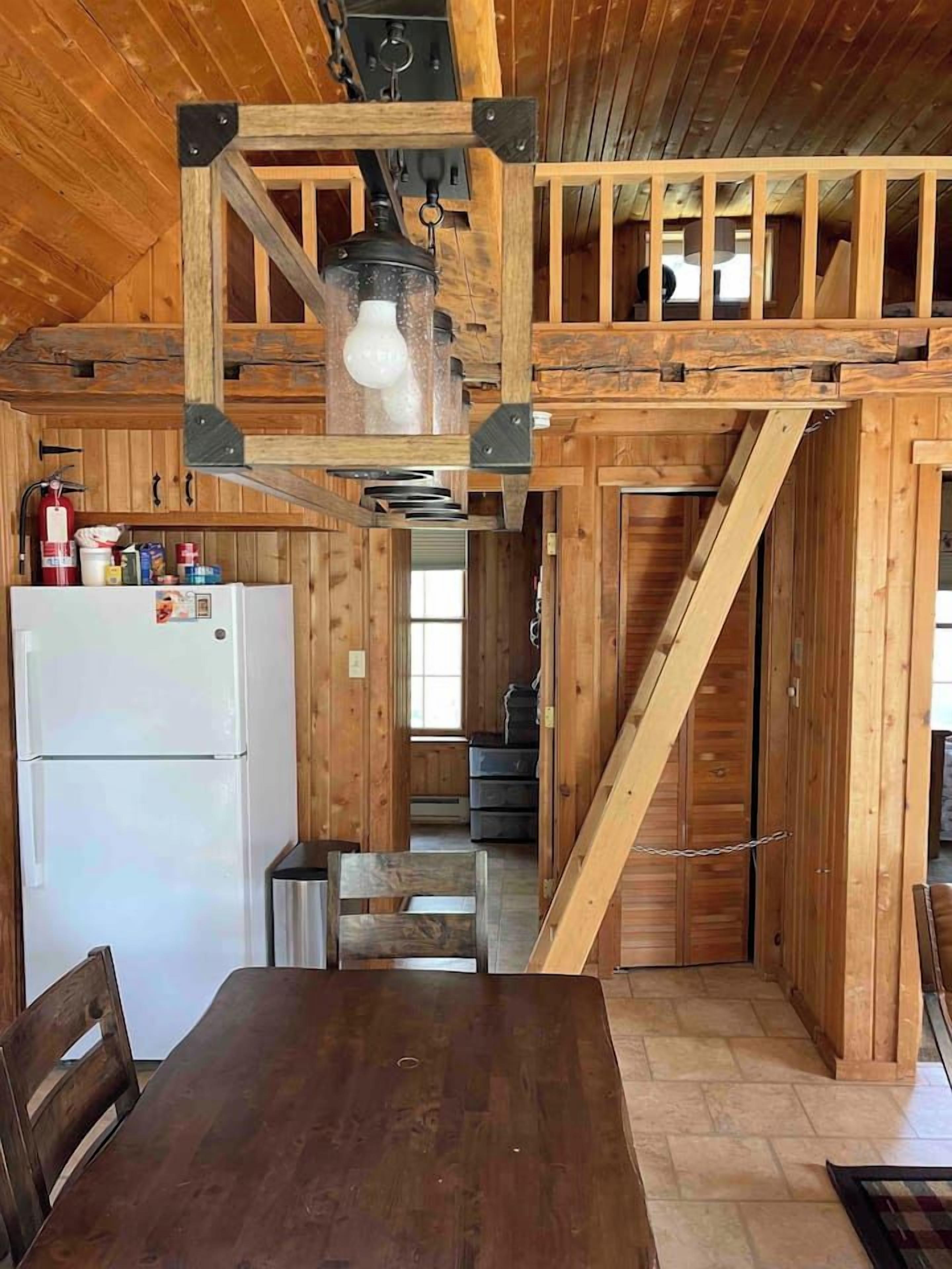 Un intérieur en bois comprenant un coin cuisine, une table à manger et un escalier.