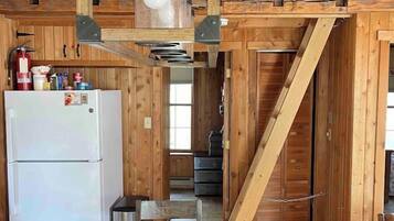 Un intérieur en bois comprenant un coin cuisine, une table à manger et un escalier.