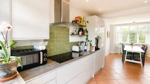 Een moderne keuken met witte kasten, een zwart aanrecht en een groene spatwand.