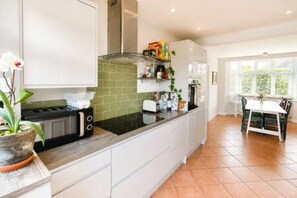 A modern kitchen with white cabinets, a black countertop, and a green backsplash.