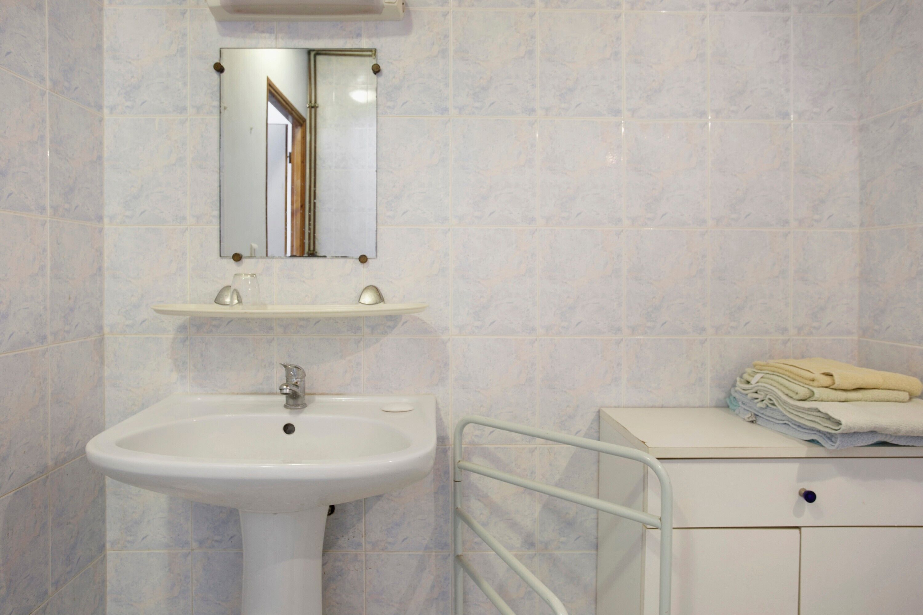 A bathroom with a white sink, a mirror, and a towel rack.