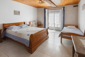 A bedroom with two wooden beds, a small table, and a chair.
