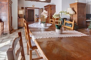 A dining area with a large wooden table, chairs, and a lace table runner.
