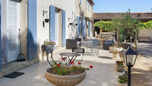A courtyard with outdoor seating, a large planter with flowers, and a street view with buildings.