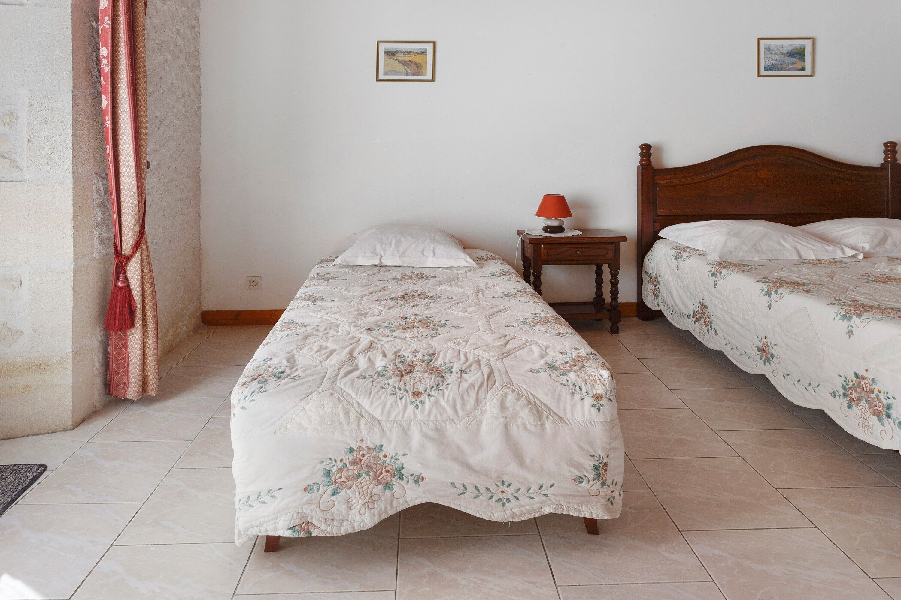Une chambre avec deux lits, une table de chevet avec une lampe et un petit tapis.