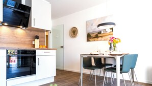A modern kitchen with a Bosch oven, a dining table with chairs, and a painting on the wall. - Dune anchor 10. balcony. Sauna. central (Grömitz)