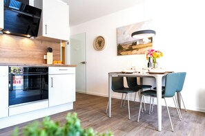 Eine moderne Küche mit einem Bosch-Ofen, einem Esstisch mit Stühlen und einem Bild an der Wand.