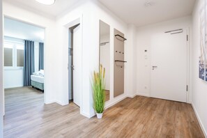 Ein Hotelzimmer mit Holzboden, einem Bett, einem Badezimmer mit Dusche und einem Flur mit Pflanze.