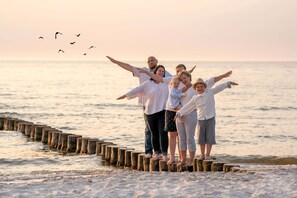 Eine Familie steht bei Sonnenuntergang auf Holzpfählen am Meer.