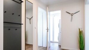 Ein Flur mit Spiegel, Deckenventilator und einer Zimmerpflanze.