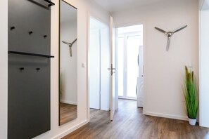 A hallway with a mirror, a ceiling fan, and a potted plant. - Dünenanker 12. Infrared cabin. Roof terrace. Central location. (Grömitz)