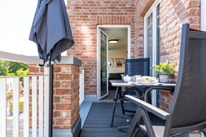 A balcony with a table, chairs, and a potted plant. - Dünenanker 12. Infrared cabin. Roof terrace. Central location. (Grömitz)