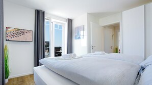 Ein Hotelzimmer mit einem großen Bett, Blick auf den Strand und einem Essbereich.