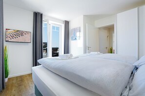 A hotel room with a large bed, a view of the beach, and a dining area. - Dünenanker 12. Infrared cabin. Roof terrace. Central location. (Grömitz)