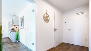 Ein moderner Flur mit Holzboden, weißen Wänden und einer Tür mit einer runden Zierde.