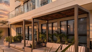 A modern outdoor seating area with cushioned benches and planters, large windows, and a clear view of the sky. - Premium loft with pools and jacuzzi near the beach (Gaira)