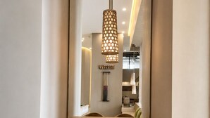 A modern dining area with a wooden table and chairs, a hanging pendant light, and a mirror reflecting the room. - Premium loft with pools and jacuzzi near the beach (Gaira)