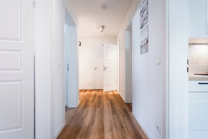 Ein Korridor mit weißen Türen, Holzböden und einer Leuchte an der Decke.