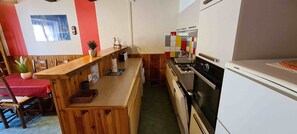 Een kleine keuken met houten aanrecht, een fornuis en een koelkast.