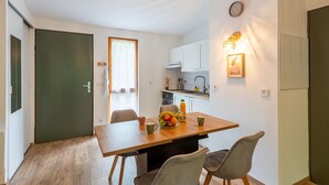 Una cucina compatta con angolo ristoro, un frigorifero e una sveglia appesa al muro.