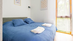 Una camera da letto con un letto, cuscini, una finestra e decorazioni alle pareti.