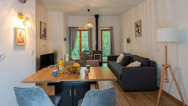 Un soggiorno moderno con un tavolo da pranzo in legno, un divano grigio e una televisione.