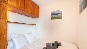 Ein Schlafzimmer mit einem Bett, weißen Kissen, einem Holzschrank und einem gerahmten Bild an der Wand.