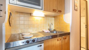 Eine kleine Küche mit eingebautem Herd, Spüle und Holzschränken.