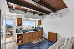Cozinha compacta com armários de madeira, painel de azulejos e vista para o exterior.