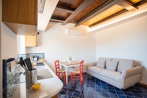 A compact living space with a kitchenette, a dining area with a table and chairs, and a sofa.