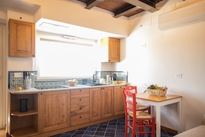 A kitchen with wooden cabinets, a window, a sink, and a red chair.