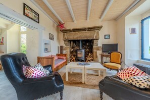 Ein gemütliches Wohnzimmer mit Kamin aus Stein, Ledersesseln, einer Holzsofa und einem Fernseher.