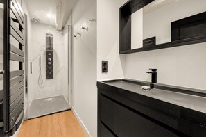 Ein modernes Badezimmer mit Dusche, Waschbecken und Spiegel.