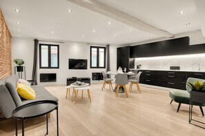 Ein stilvolles Wohnzimmer mit Sofa, Couchtisch und Essbereich mit Stühlen.