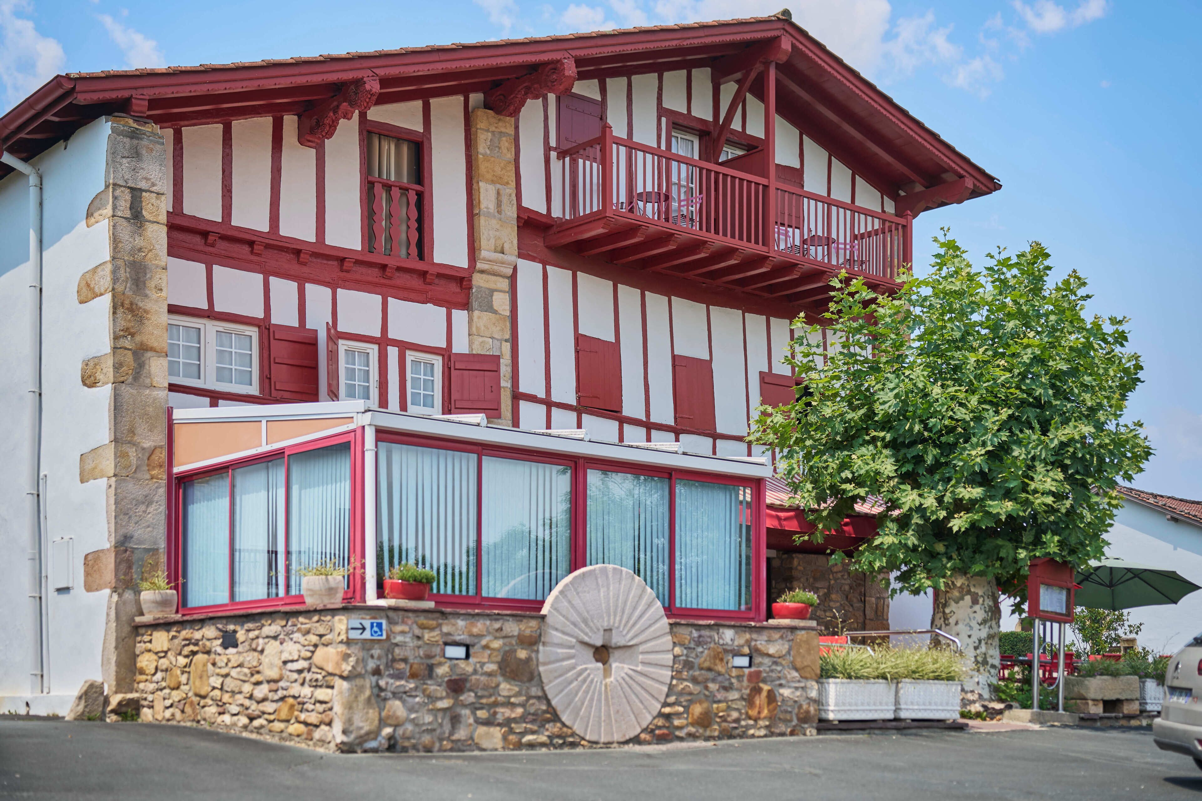 Un bâtiment traditionnel à colombages, avec une base en pierre, de grandes fenêtres et un balcon.