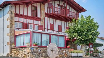 Un bâtiment traditionnel à colombages, avec une base en pierre, de grandes fenêtres et un balcon.