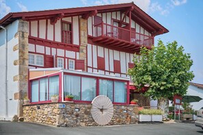A traditional half-timbered building with a stone base, large windows, and a balcony.