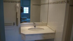 A bathroom with a white sink, a handheld hair dryer, and a mirror. - Pikassaria (Sare)