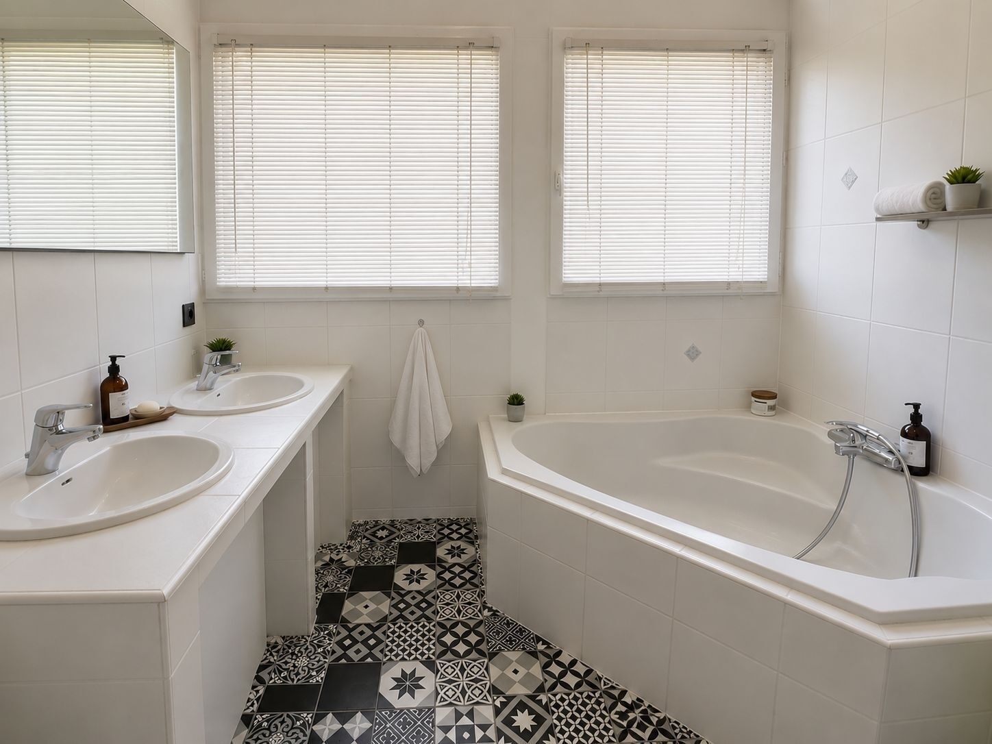 Un bagno con due lavandini, una vasca e piastrelle a motivi decorativi.