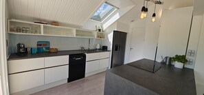 A modern kitchen with white cabinetry, a dishwasher, a coffee machine, and a built-in oven. - Villa Blanche - Entre montagne, piscine et calme (Sévrier)